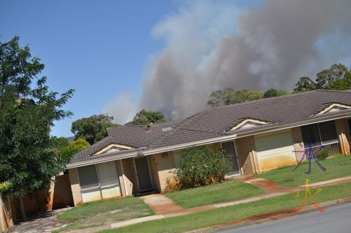 The smoke is from the hills behind the house, not the house itself