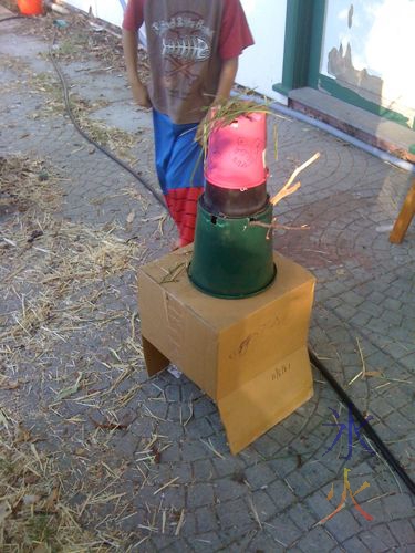 Scarecrow constructed of a cardboard box, a couple of flowerpots, sticks for arms, grass for hair. And a scary face drawn on the flower pot.