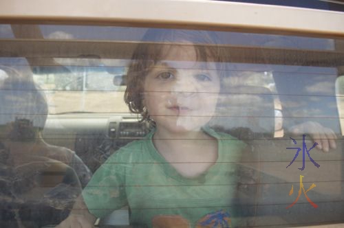 Toddler with face pressed up against the rear glass window of a car