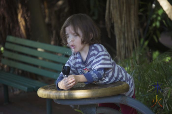 Toddler getting water up nose while attempting to drink from a water fountain