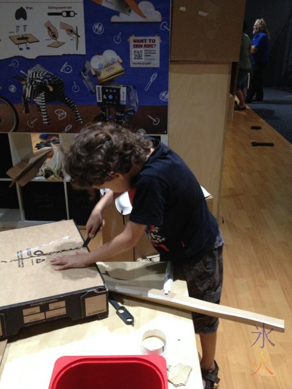 8yo sawing cardboard with a Makedo tool