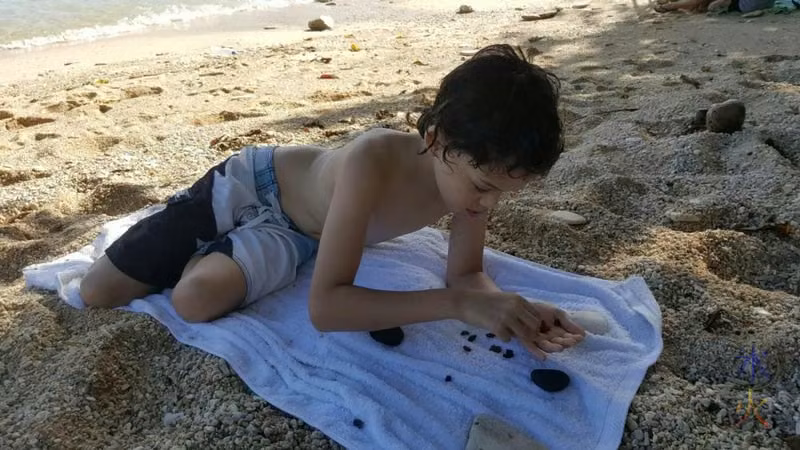 12yo making glass rock patterns with worn glass pieces at Flying Fish Cove, Christmas Island