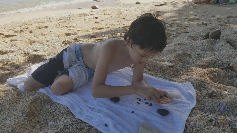 12yo making glass rock patterns with worn glass pieces at Flying Fish Cove, Christmas Island