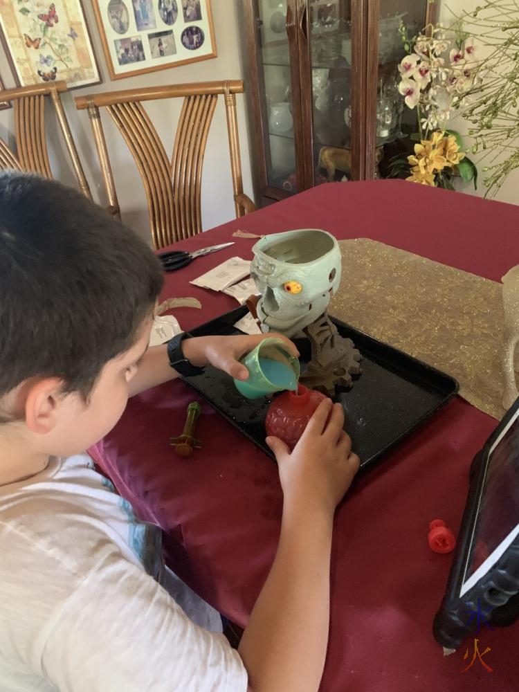 9yo pouring drink mix into zombie brain science kit thing