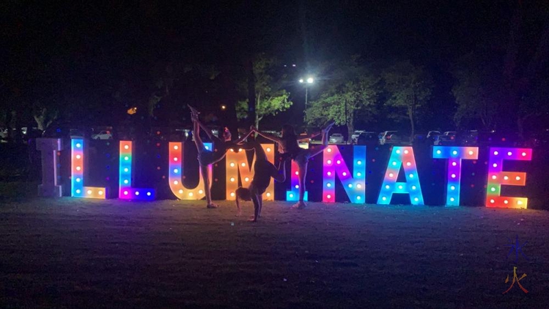 13yo and gymnastics friends posing in front of Illuminate letters