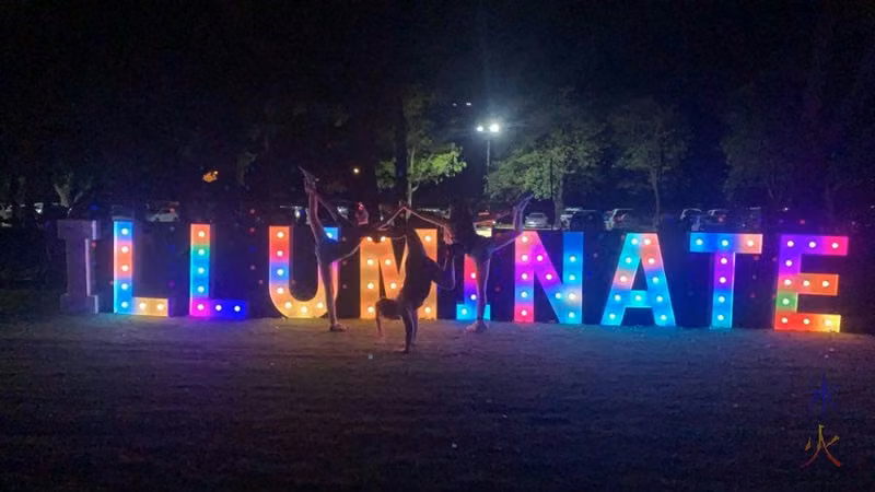 13yo and gymnastics friends posing in front of Illuminate letters