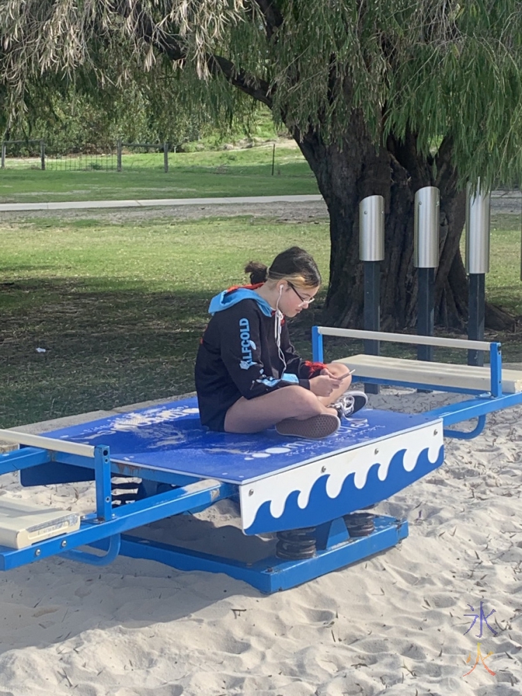 13yo editing videos on her phone on a see saw at AP HInds Reserve, Bayswater, Western Australia