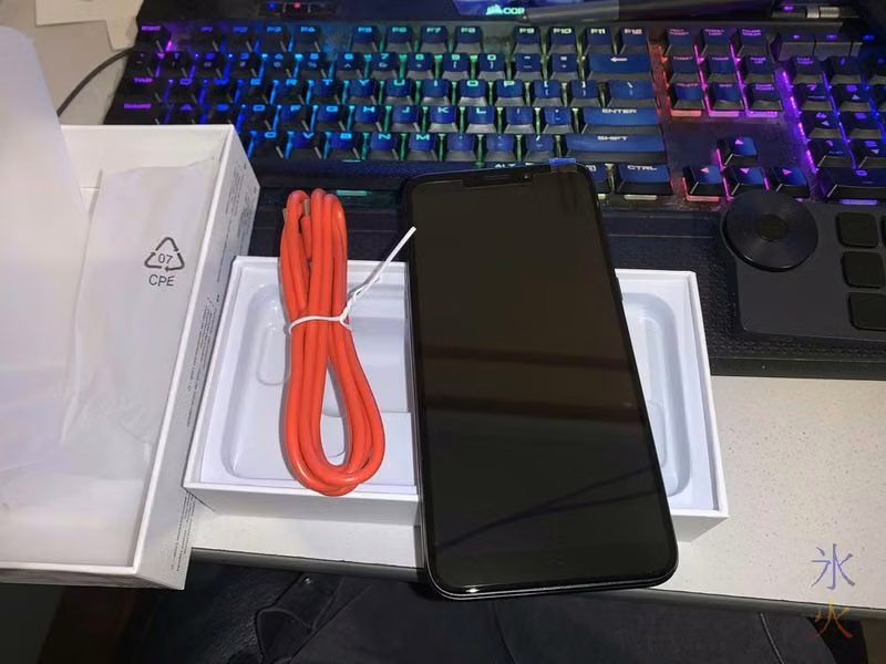 PinePhone Pro and bright red charge cable sitting on top of PinePhone Pro box