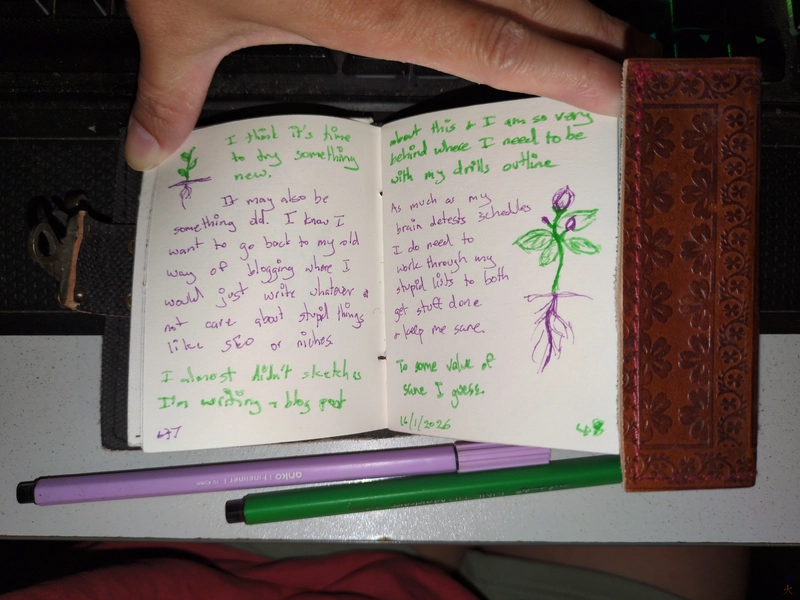 journal entry and imaginary plant sketches in a tiny book with the green and purple pen used to write/draw