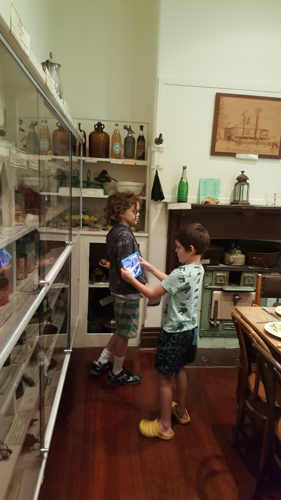 11yo and 7yo checking out a room done up similar to the kitchen but that wasn't the original kitchen, including displays of stuff that would have been in the kitchen.  Azelia Ley Homestead, Hamilton Hill, Western Australia