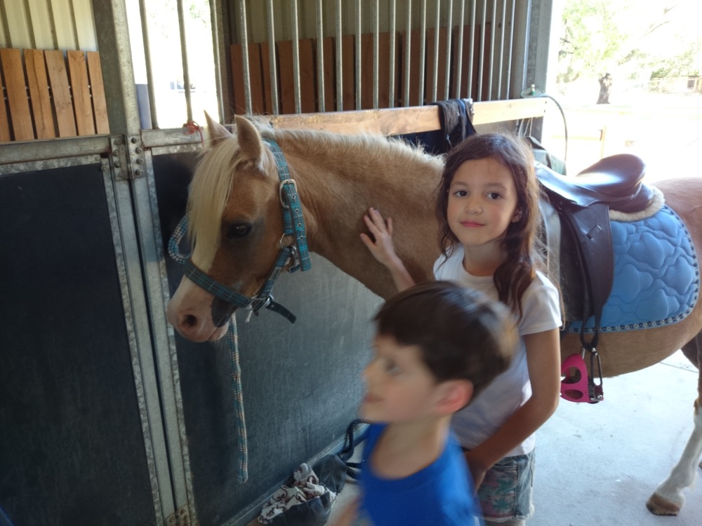8yo with her riding lesson pony (and 6yo blurring across the foreground)