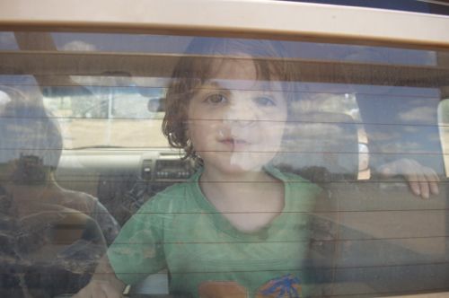 Toddler with face pressed up against the rear glass window of a car