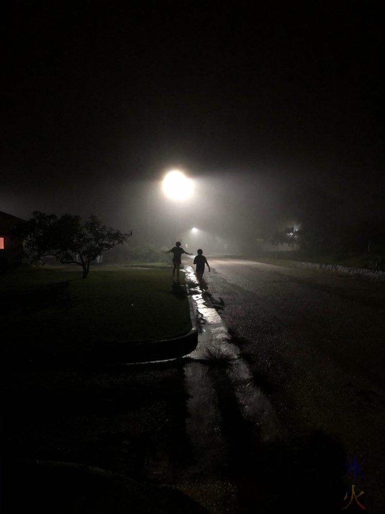 kids running up a dark street, looks like the beginning of a horror movie